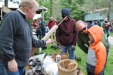 Bob Berg shows a primitive flint tool to a family at Primitive Pursuits Day in Ithaca, New York